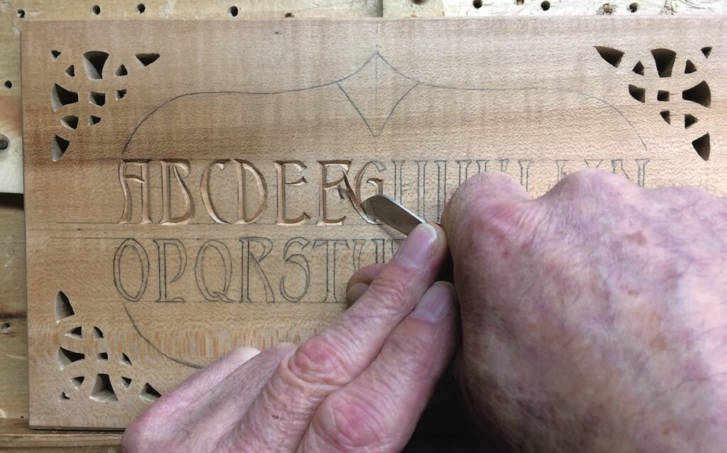Hand carving alphabet letters into wooden board