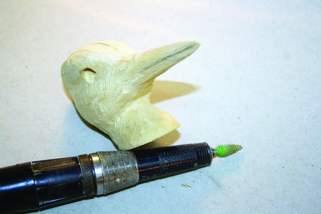 Wood carving and carving tool on table.