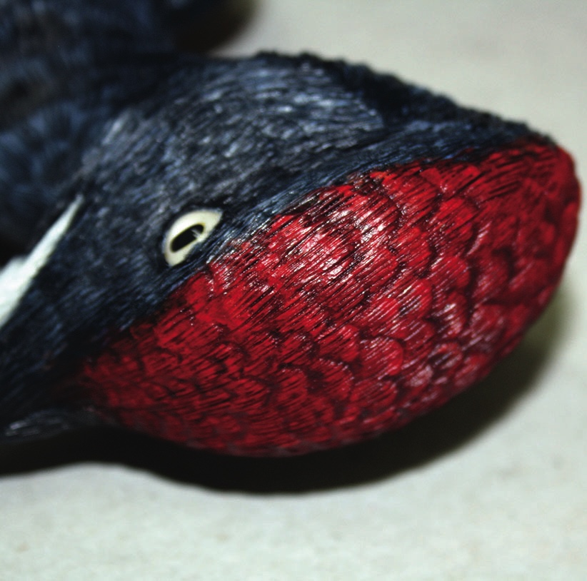 Close-up of bird figure with red textured head