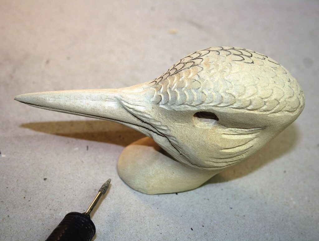 Wooden bird head carving with a fine tool.