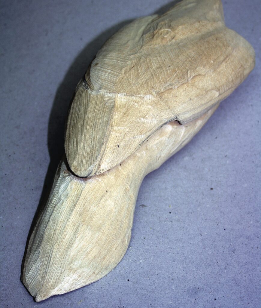 Wooden platypus carving on a grey background.