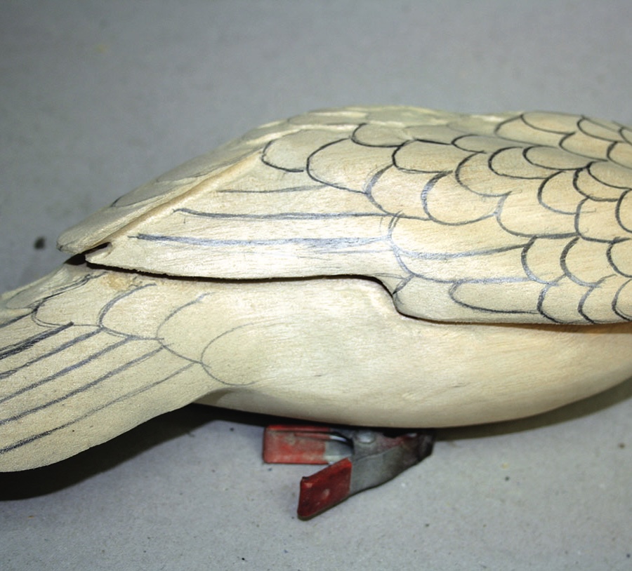 Wooden bird with carved wing details and clip legs.