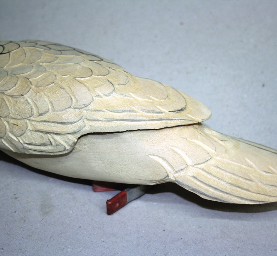 Carved wooden bird with detailed feathers.