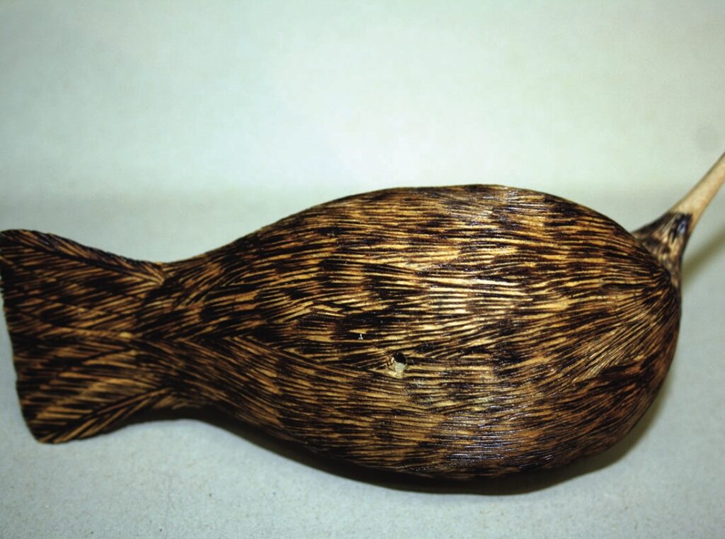 Wooden carving of a seal figure.