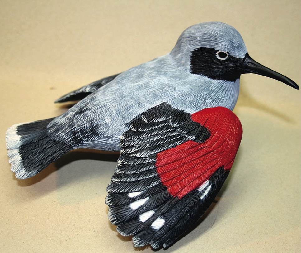 Colourful bird sculpture with red and black wings.