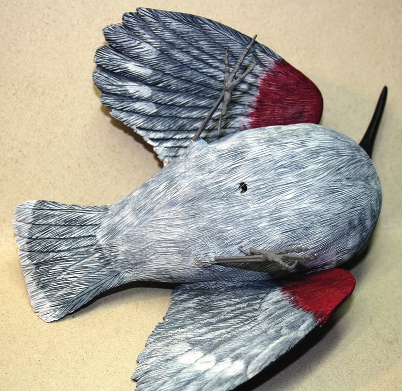 Red and grey bird sculpture lying on side