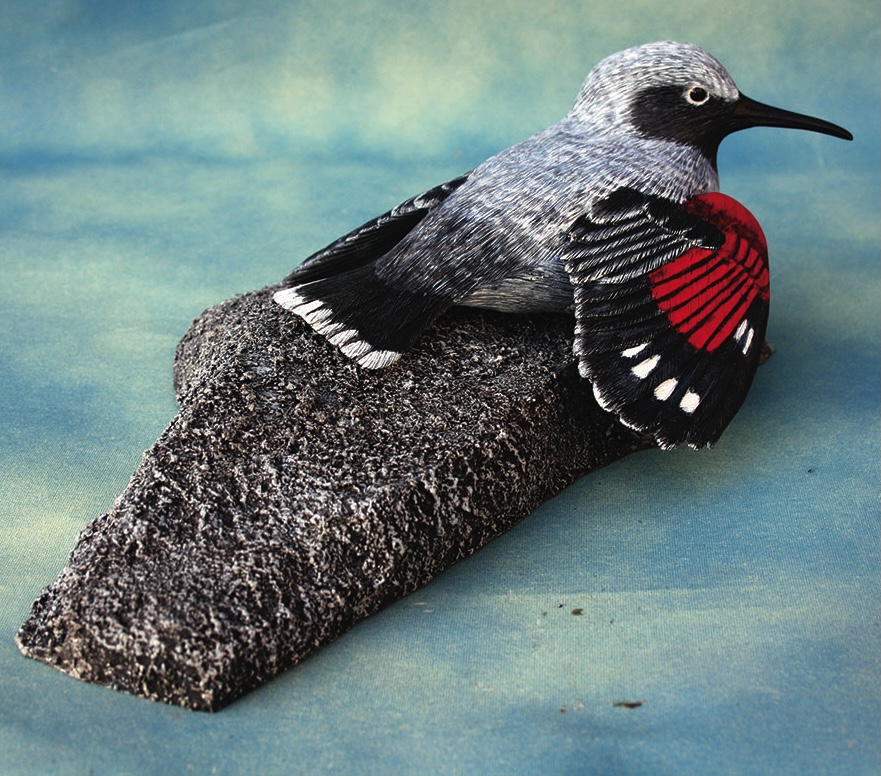 Red-winged bird on textured rock sculpture.