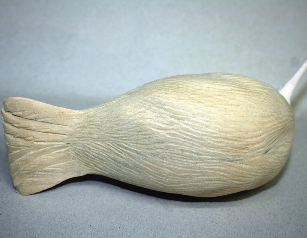 Wooden fish carving on grey background.