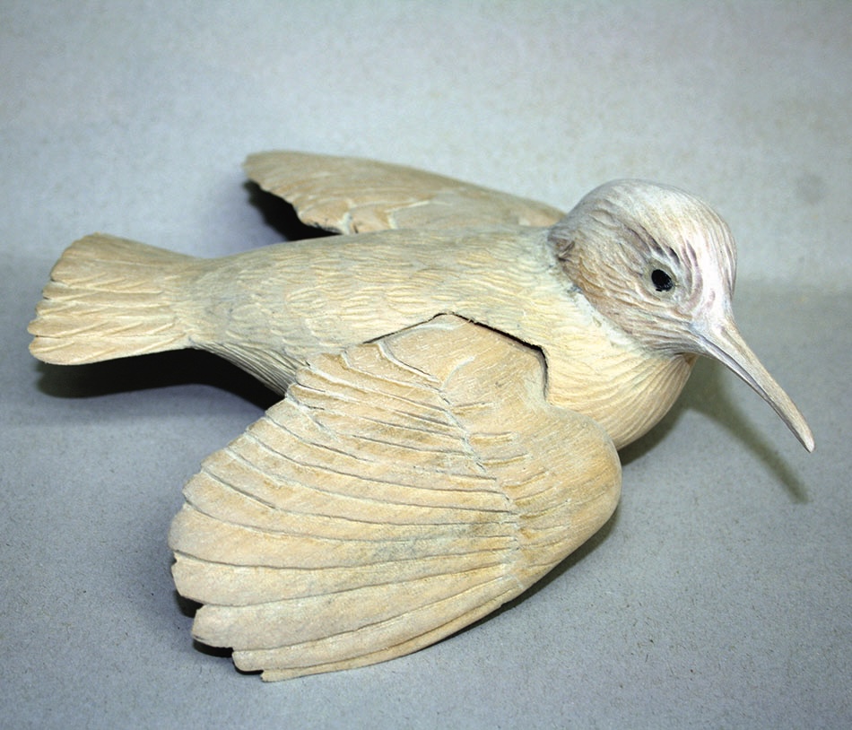 Wooden bird sculpture on grey surface.