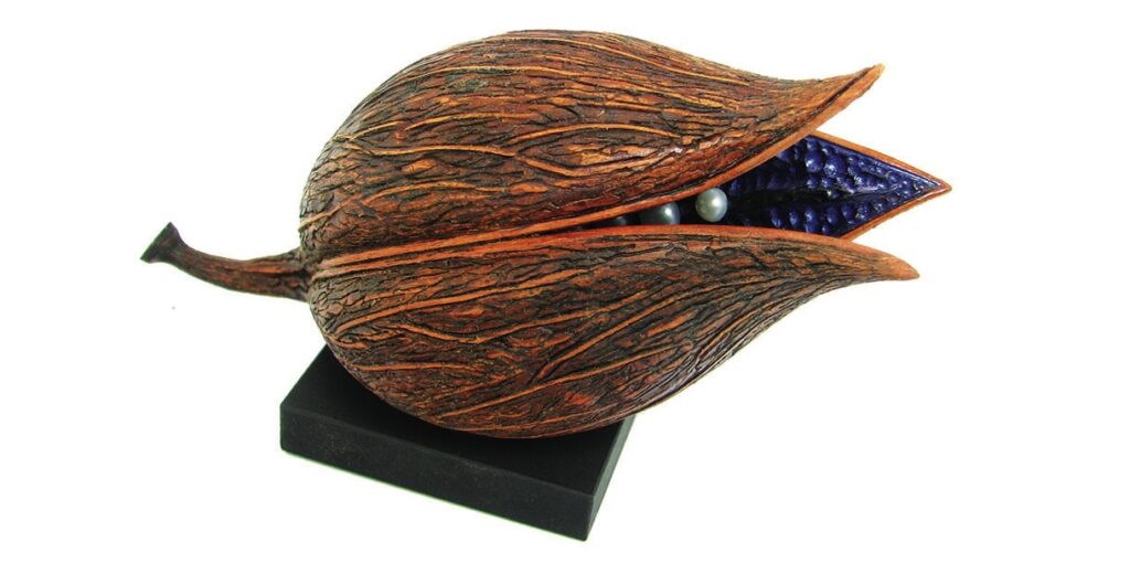 Decorative wooden seed pod sculpture on black base.
