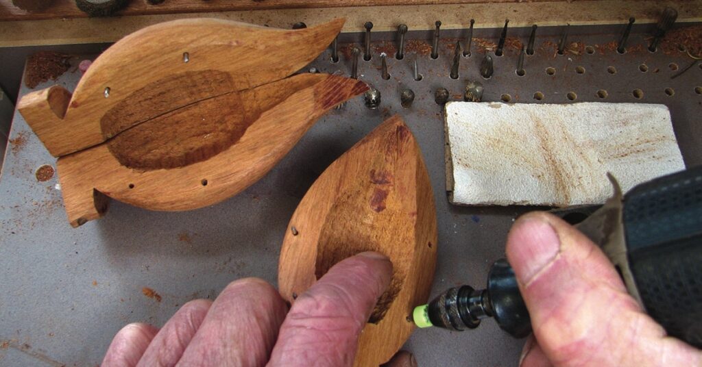 Carving wooden fish using a handheld rotary tool.
