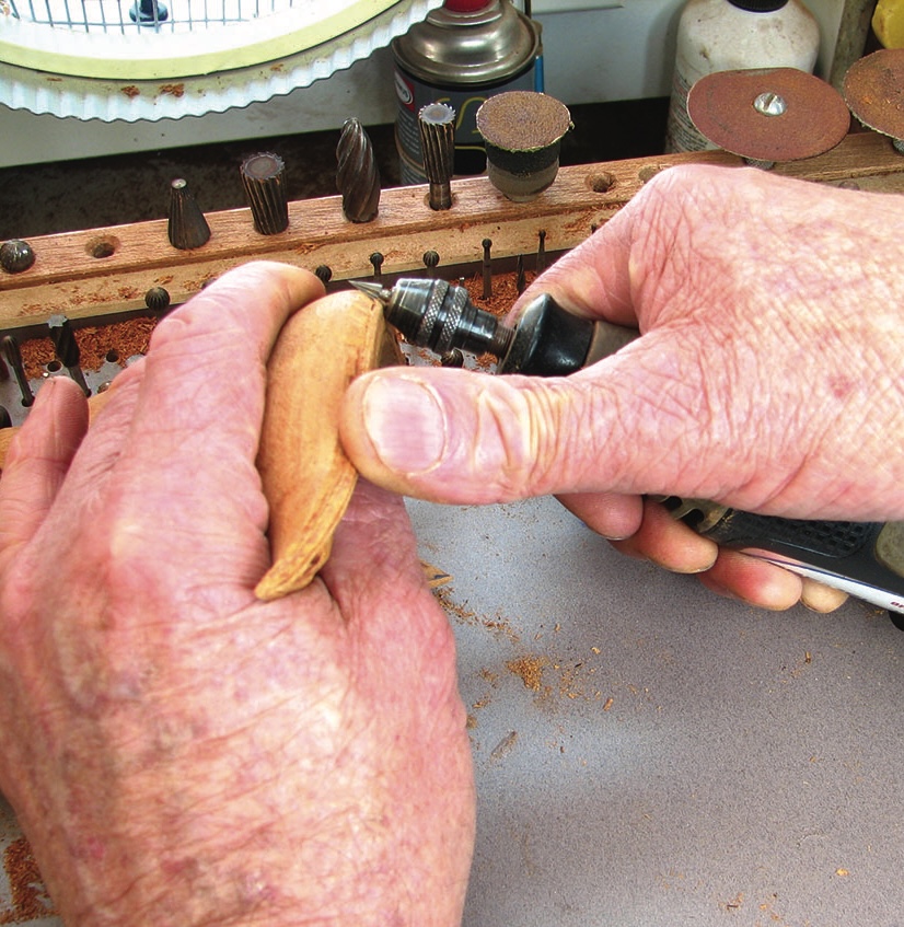 Woodcarving with rotary tool in workshop.
