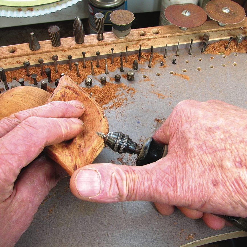 Person carving wood with drill and bit set.