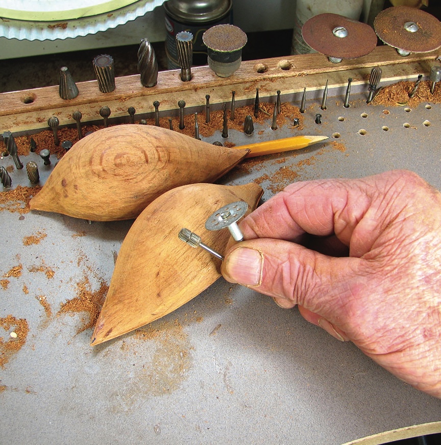 Carving wood with rotary tool bits on table.