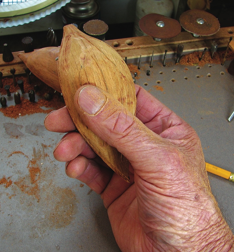 Hand holding carved wooden piece.