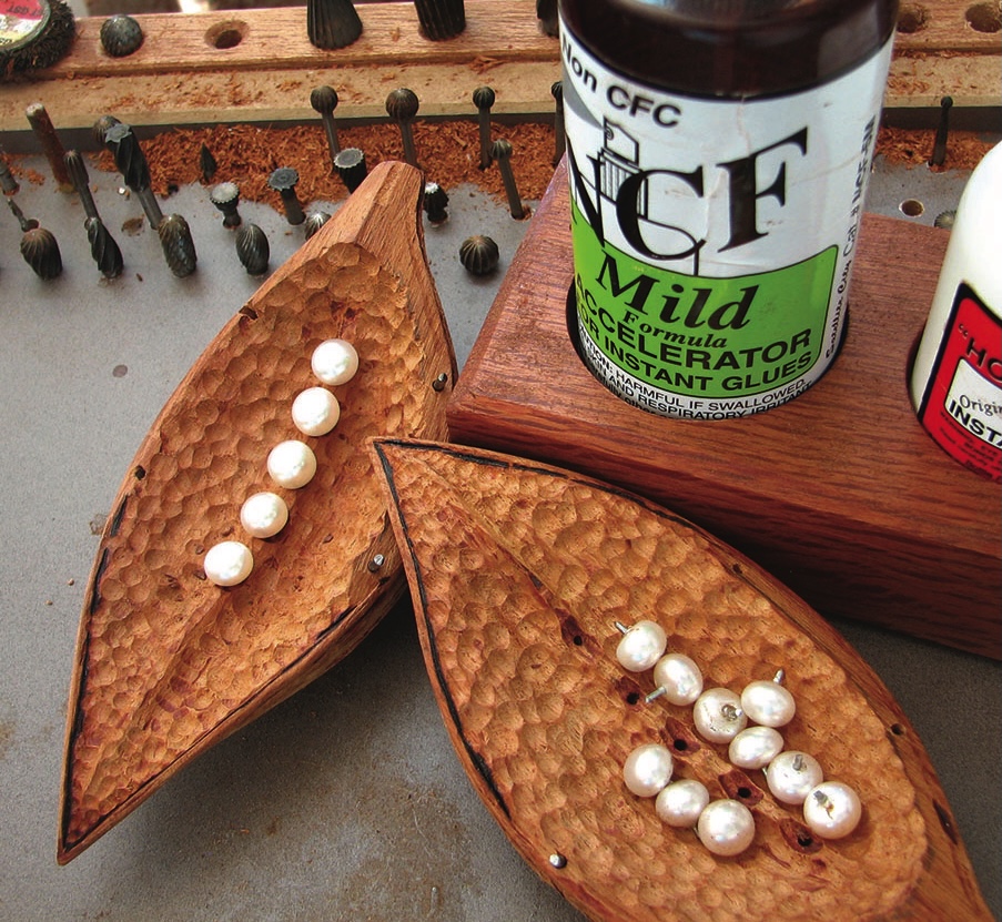 Wooden case with pearls and glue bottle.