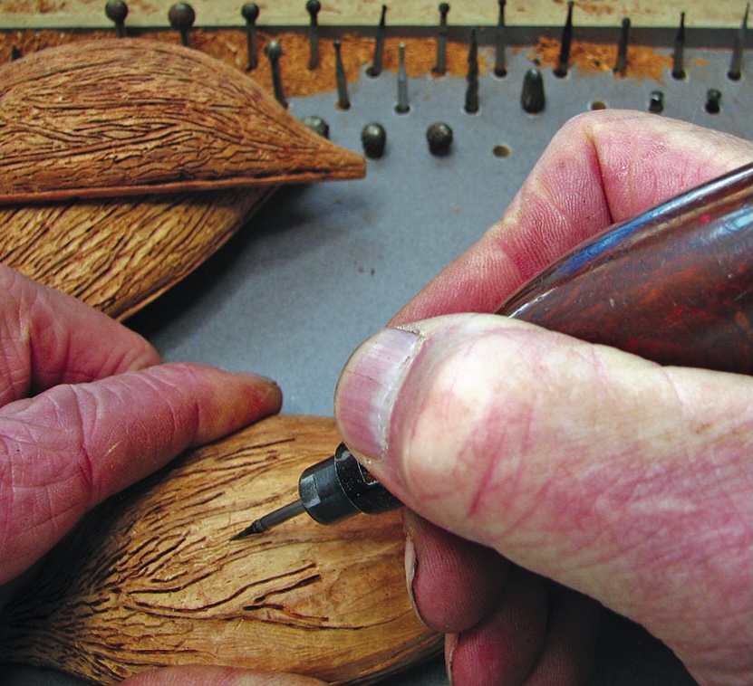 Hands carving intricate patterns into wood.