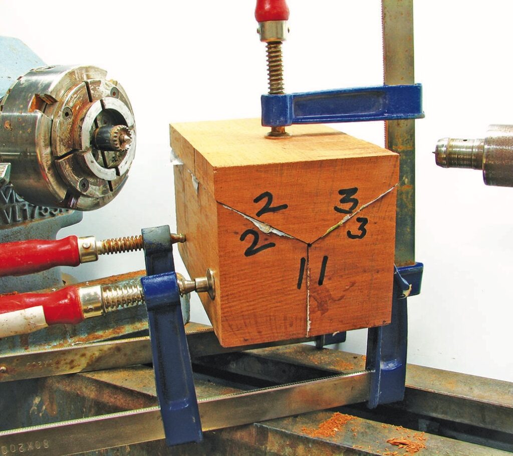 Wood block clamped on metal lathe for turning.