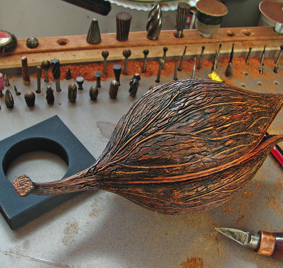 Intricate wood sculpture with carving tools displayed nearby.