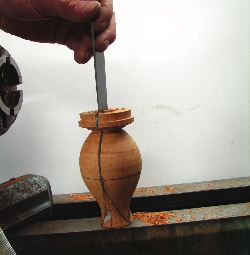 Woodturning tool cutting open a wooden vase.