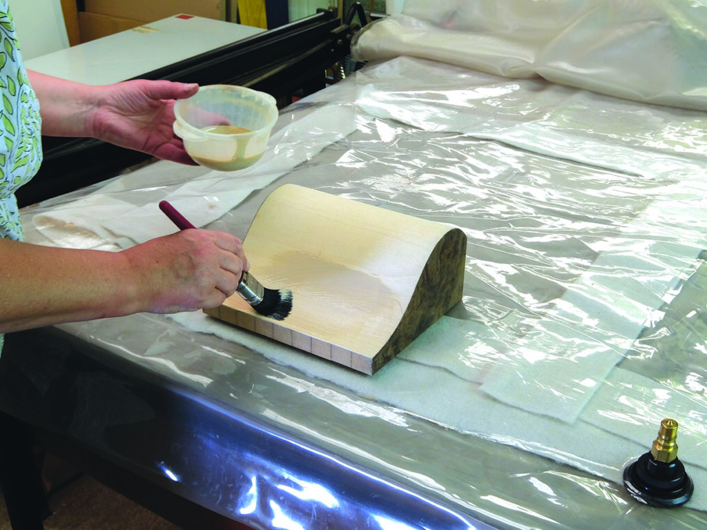Applying glue to curved wood on plastic sheet.