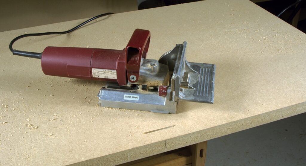 Electric biscuit joiner on a wooden surface.