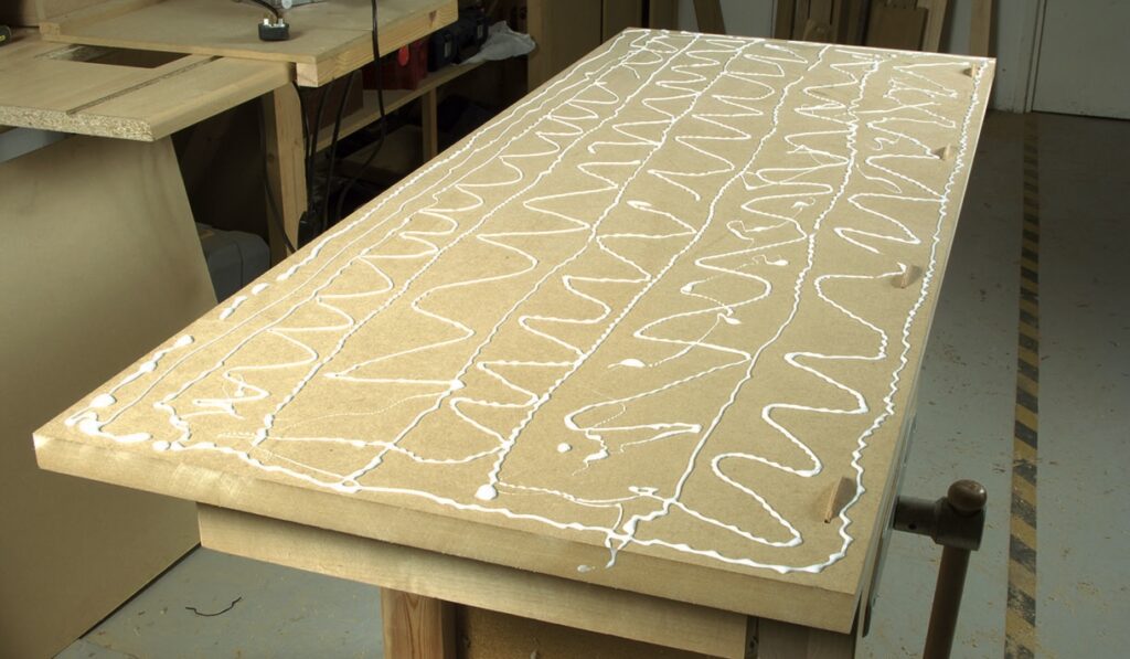 Woodwork glue on MDF board, preparation for assembly.