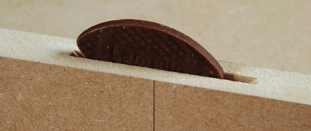 Wood biscuit joiner in wood panel slot.