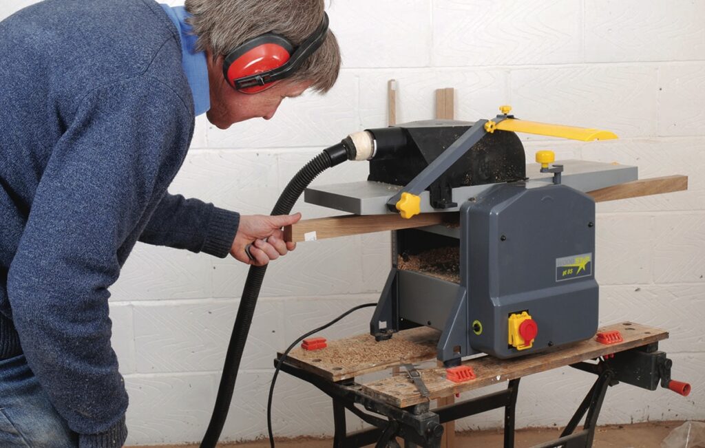 Man using wood thicknesser in workshop