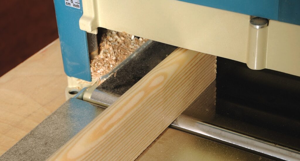 Wood planer smoothing wooden plank.