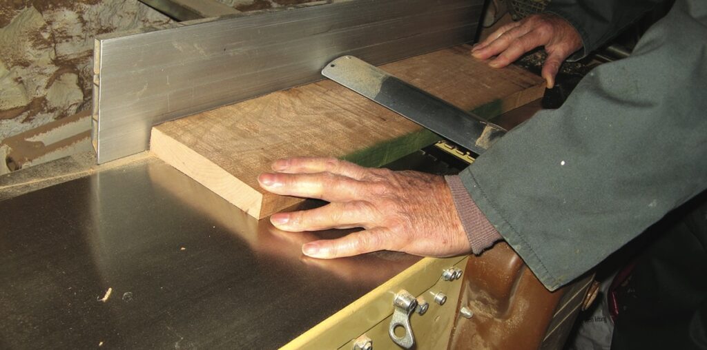 Carpenter shaping wood with planer.