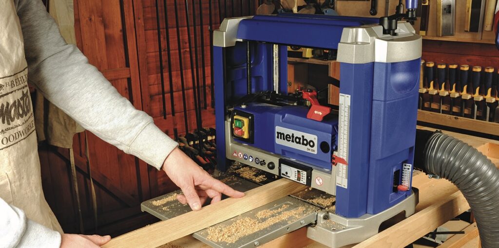 Man using woodworking planer in workshop.