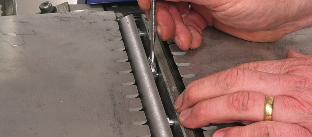 Hands using a spanner on machine joint