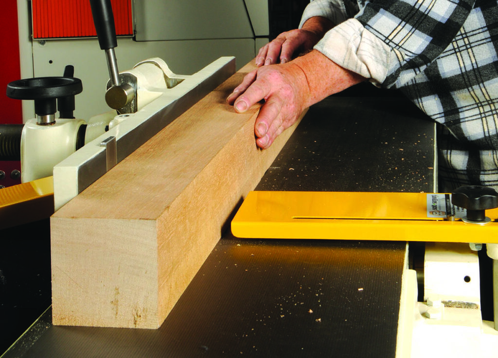 Hands using planer on a wooden beam.