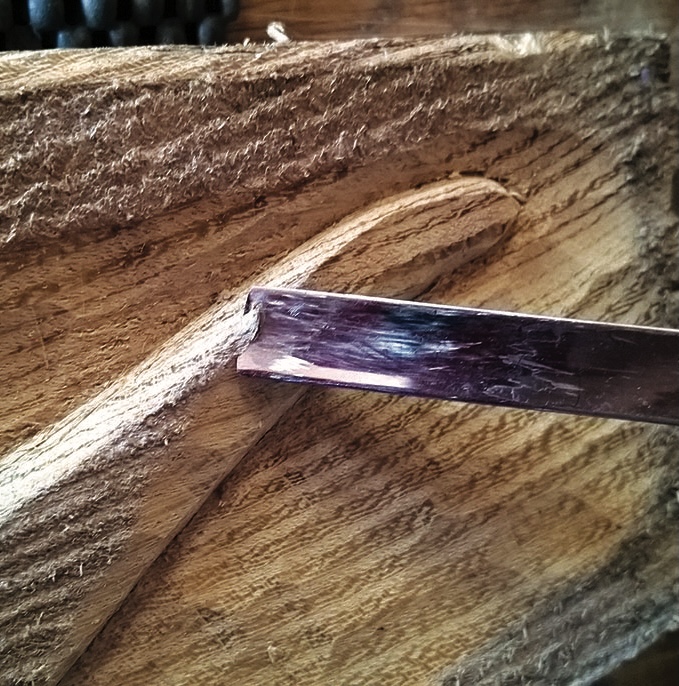 Wood carving with a chisel creating a groove.