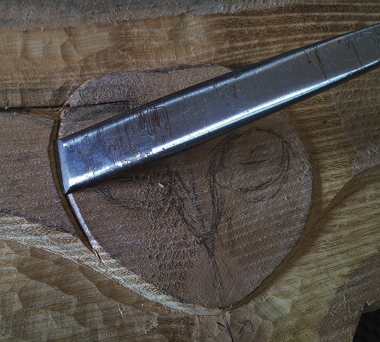 Chisel carving wood with floral design sketch.