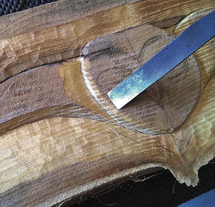 Wood carving in progress with chisel tool.
