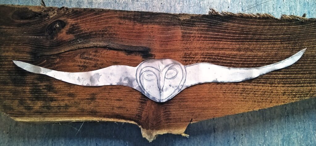 Metal owl shape on rustic wooden background.