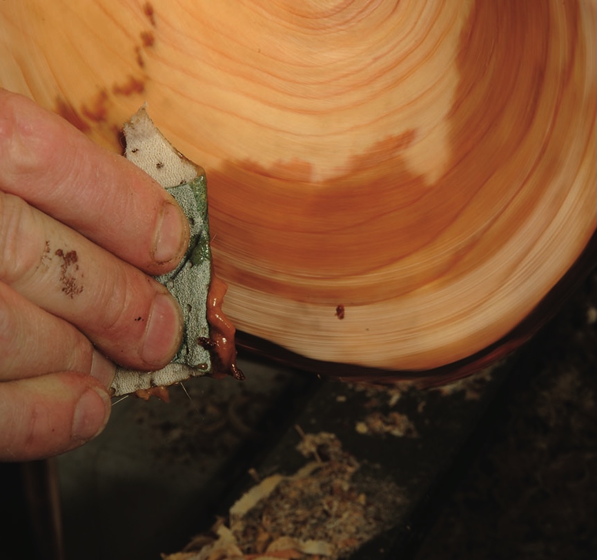 Hand sanding wood on a lathe