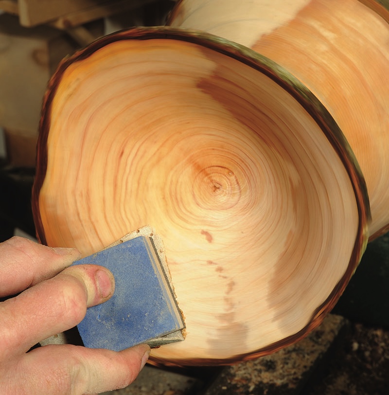 Sanding wooden bowl on a lathe.