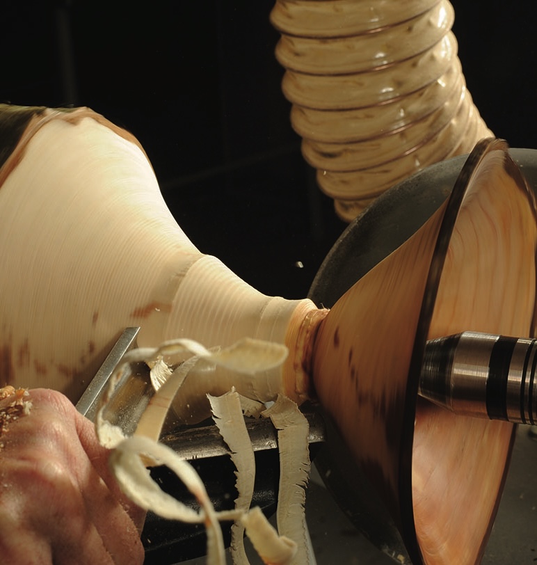 Wood being turned on a lathe by hand.