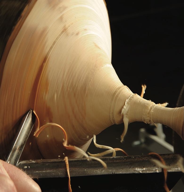 Woodturning with lathe tool and wood shavings.