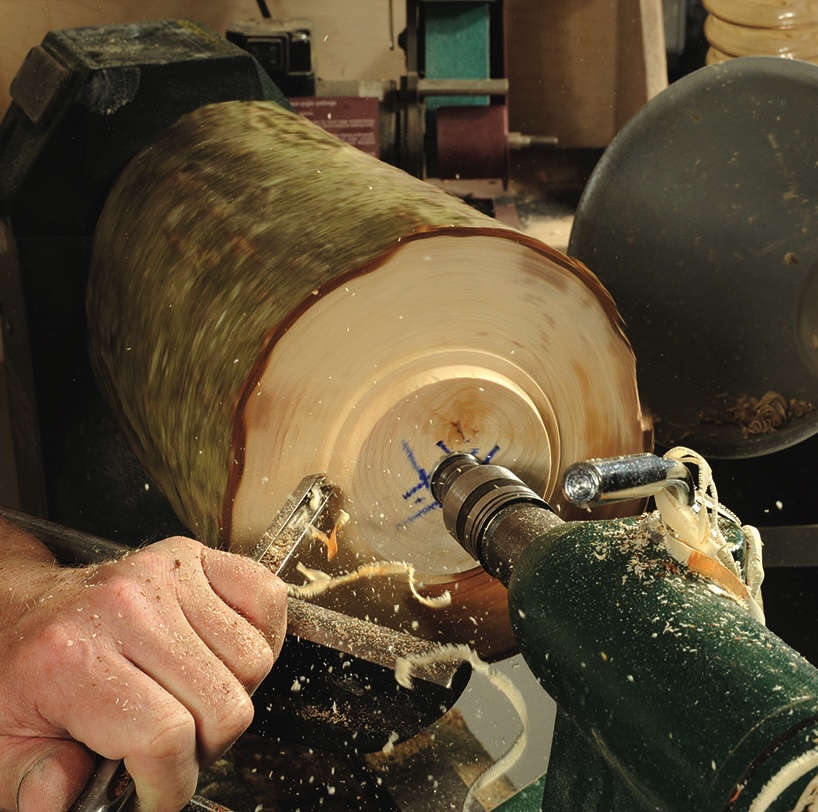 Woodturning with lathe by craftsman in workshop.