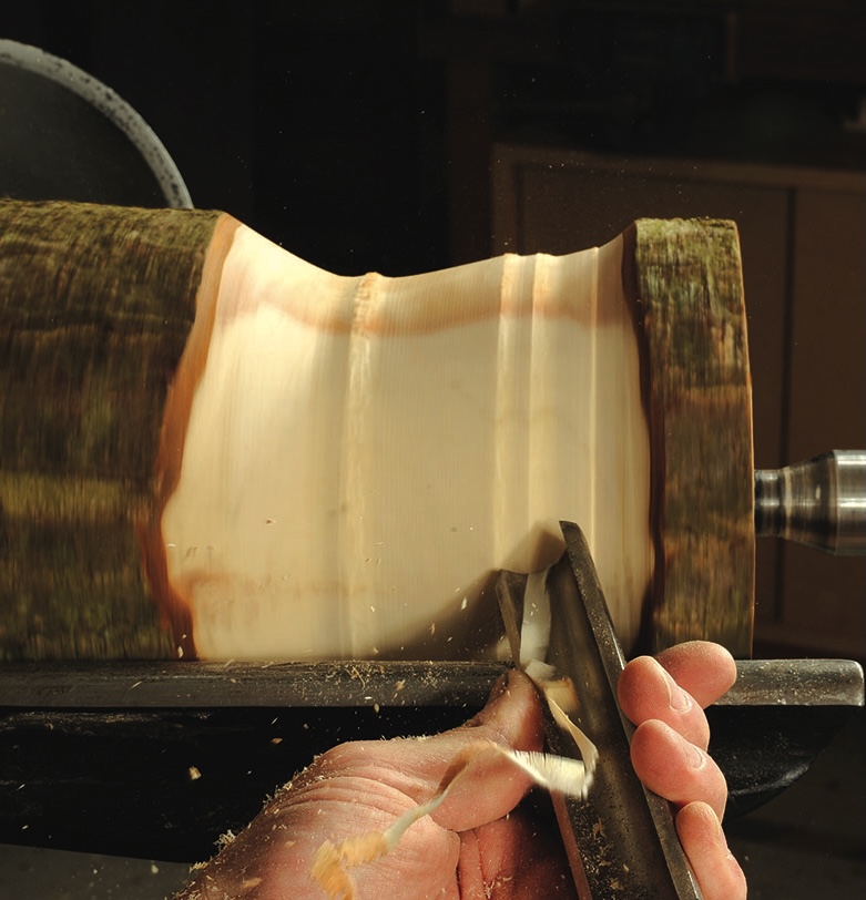 Woodturning with chisel on spinning wood lathe.