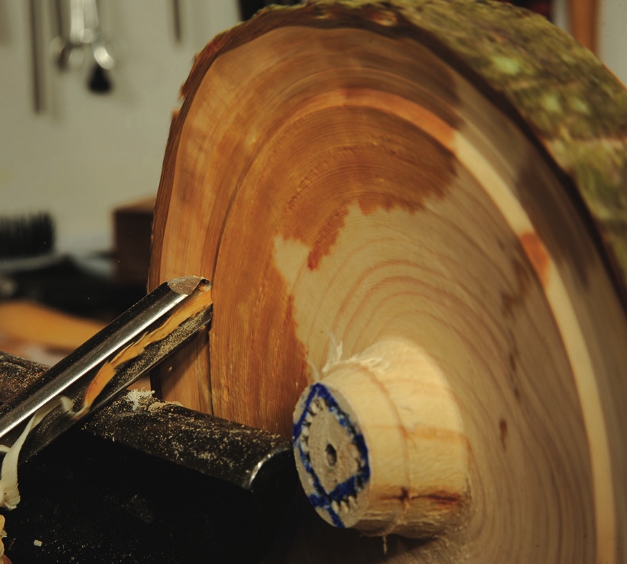 Woodturning with chisel on spinning lathe.