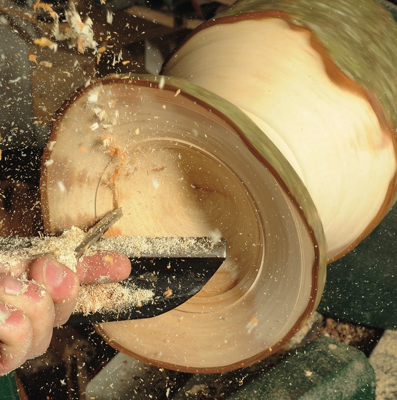 Woodturning process creating wooden bowl on lathe