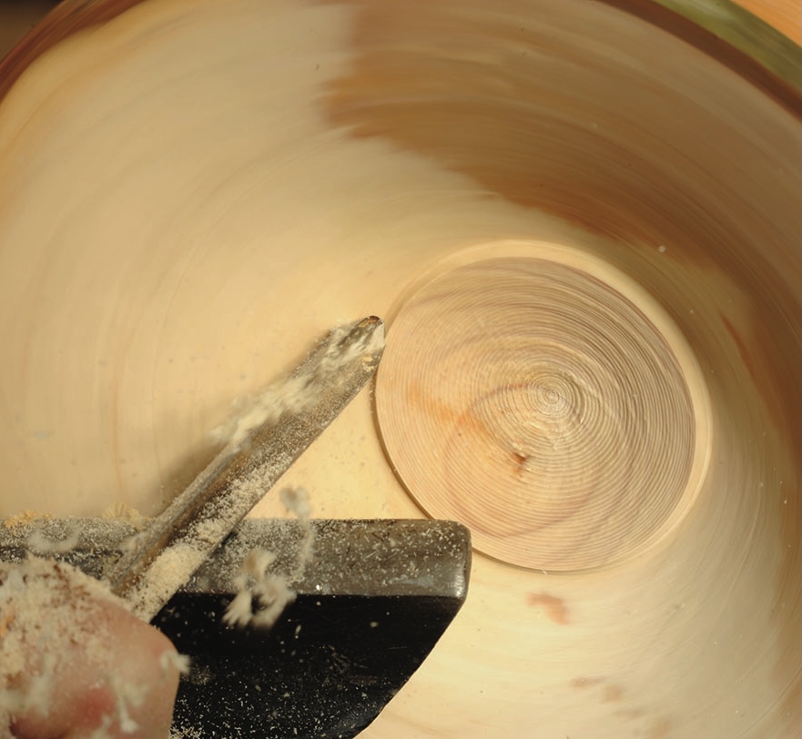 Close-up of woodturning process on lathe with tool.