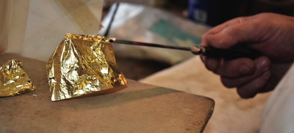 Hand applying gold leaf with knife