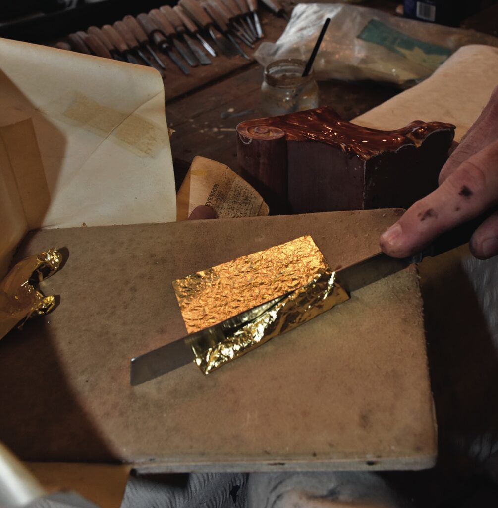 Manual gold leaf application on a surface.