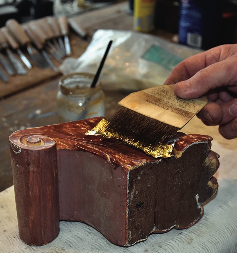 Applying gold leaf to wooden sculpture
